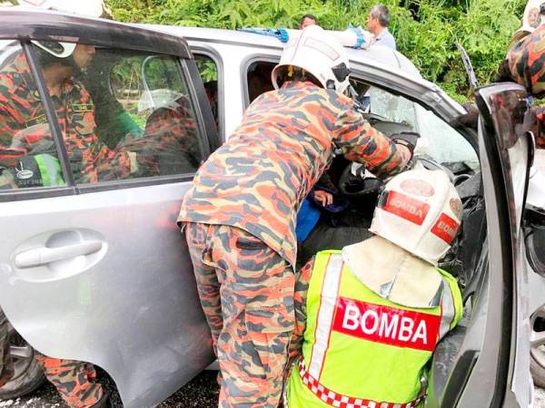 Anggota bomba dari Balai Bomba dan Penyelamat Simpang Pulai menjalankan operasi mengeluarkan mangsa yang tersepit dalam Perodua Myvi hari ini. - Foto JBPM Perak