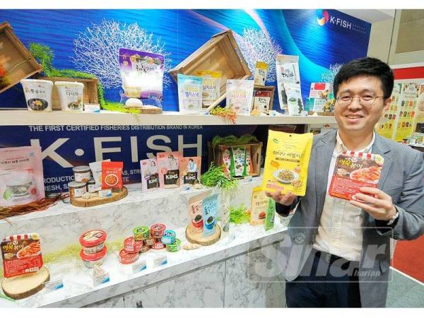 Dong Jun bersama produk-produk makanan laut Korea yang mana sebahagiannya sudah berada di pasaran Malaysia. - FOTO ROSLI TALIB