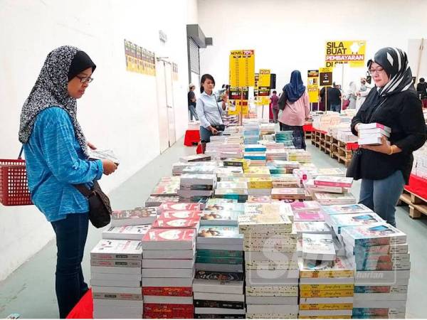 Pengunjung leka memilih novel di Jualan Gudang Akhir Tahun Karangkraf.