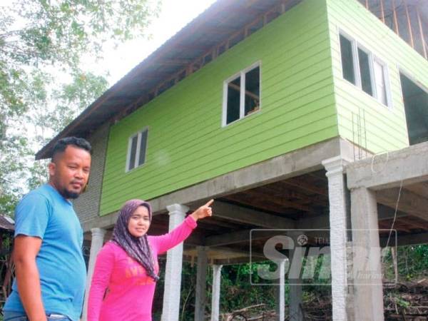 Jasma Asmida (kanan) bersama suami menunjukkan rumah baharu mereka di Kampung Lachang.