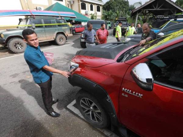 Mohd Zarin (kanan) memeriksa kenderaan pacuan empat roda yang disita selepas pemiliknya ditahan kerana berada dalam Hutan Simpan Kekal Berkelah tanpa permit.