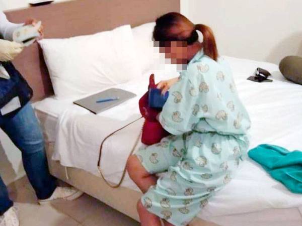 Anggota imigresen memeriksa dokumen perjalanan salah seorang wanita yang ditahan dalam operasi terbabit.