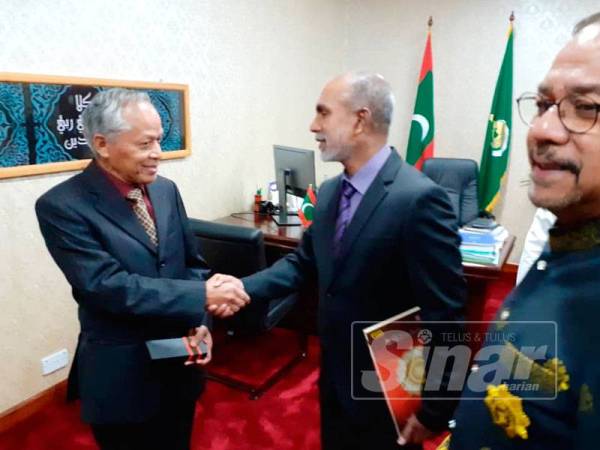 Nasir (kiri) bersalaman dengan Dr Ahmed Zahir Ali (kanan) selepas menyerahkan al-Quran sebagai cenderhati.