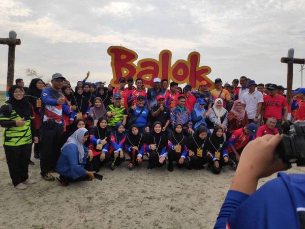 Peserta bergambar di hadapan papan tanda Pantai Balok sebelum memulakan acara mengutip sampah sempena program Sayangi Pantai Kita di Pusat Rekreasi Balok di sini hari ini.