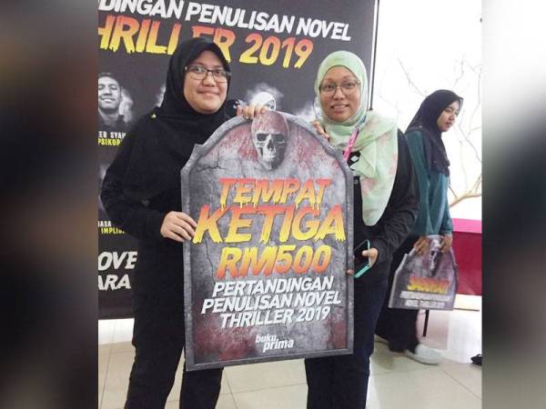 Firdaus (kanan) menyampaikan hadiah untuk tempat ketiga dalam Pertandingan Penulisan Novel Thriller anjuran Buku Prima.