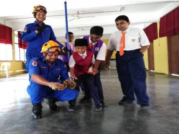 Murid SK Sultan Abdul Aziz, Kampung Kuantan melihat anak ular sawa yang berjaya ditangkap APM menggunakan penjerut pagi tadi.