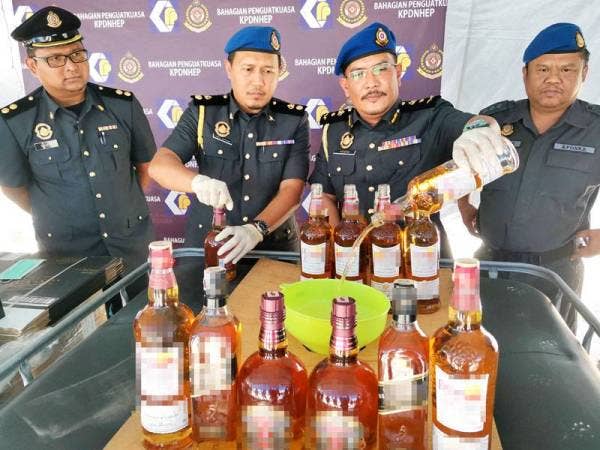 Azizan (dua dari kanan) menunjukkan gimik pelupuskan arak tiruan di Kompleks Penyimpanan Bahagian Penguatkuasa KPDNHEP di sini hari ini.