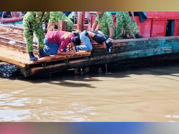 Anggota penguatkuasa memeriksa bahagian bawah bot nelayan bagi mencari nelayan yang cuba bersembunyi ketika operasi diadakan. - Foto ihsan APMM