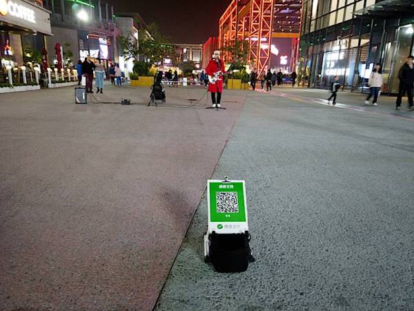 PENYANYI jalanan meletakkan Kod Quick Response (QR) miliknya bagi membolehkan orang ramai memberi sumbangan melalui aplikasi bebas tunai Wechat Pay.