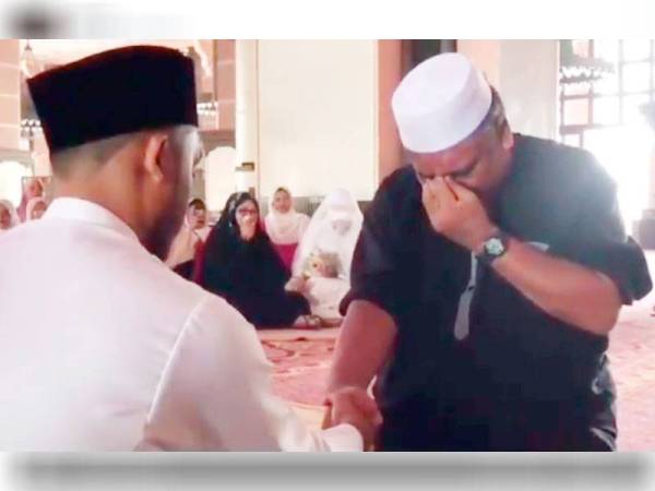 Tangkapan layar video memaparkan ayah Yasmin sebak masa menjadi wali menggenggam tangan suaminya ketika akad nikah dijalankan.