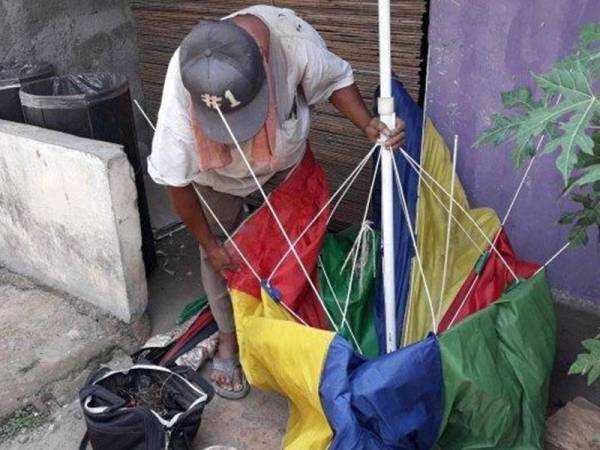 Pak Sadi membaiki payung salah seorang pelanggannya.