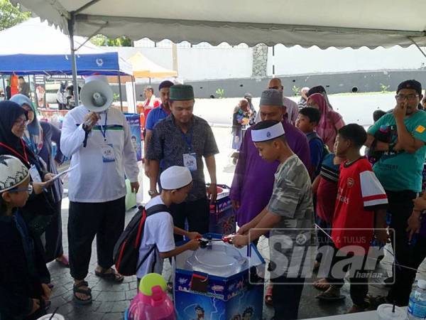 Mohd Asna (tiga dari kiri) melihat pertandingan bayblade yang dijalankan hari ini.