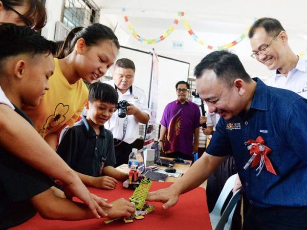 Menteri Pendidikan, Dr Maszlee Malik yang juga Ahli Parlimen Simpang Renggam beramah mesra di samping mencuba robot ciptaan murid-murid Sekolah Jenis Kebangsaan (C) Tah Tong Pontian ketika lawatan kerja beliau ke sekolah-sekolah hari ini. -foto: BERNAMA