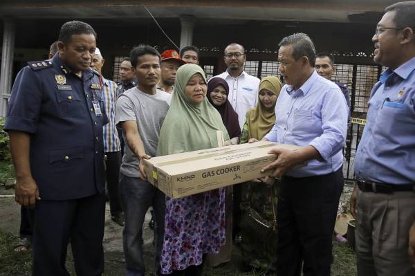 Aminuddin (dua dari kanan) menyerahkan bantuan awal kepada mangsa kebakaran Siti Fatimah Bador (tiga dari kiri) ketika menziarahi ahli keluarga mangsa di Kampung Surau Selemak hari ini. - Foto Bernama