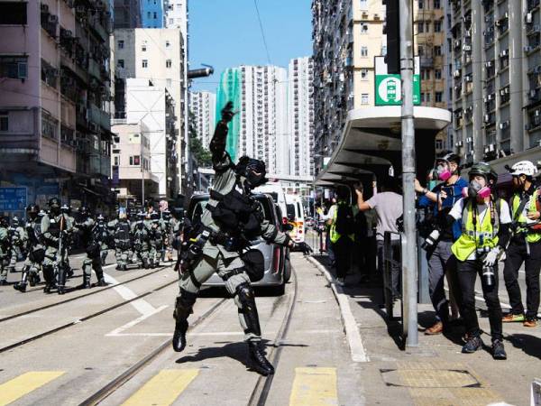 Seorang anggota polis melempar bom gas pemedih mata ketika menyuraikan penunjuk perasaan di Hong Kong. - Foto AFP