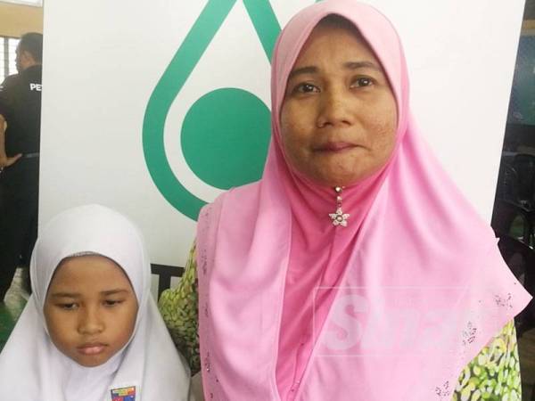 Mariyam bersama anaknya, Nur Alis yang terpilih menerima bantuan peralatan sekolah yang disalurkan oleh Yayasan Petronas.