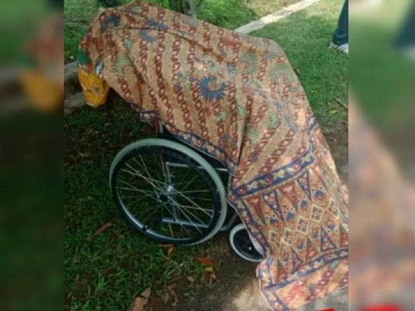 Suspek yang meletakkan mayat ibunya di atas kerusi roda ditahan oleh orang awam. - Foto ihsan pembaca