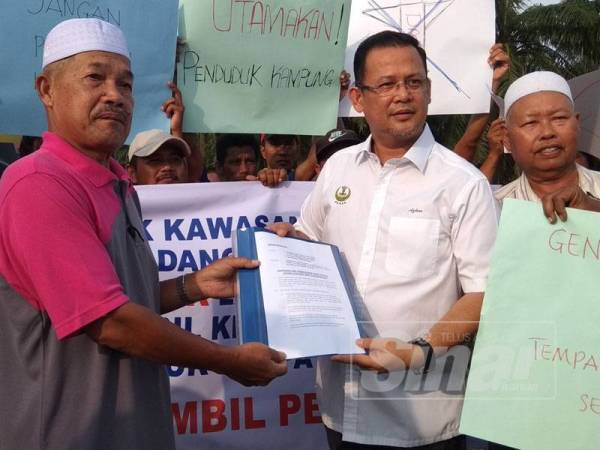 Alias (kiri) menyerahkan memorandum penduduk kepada Mohd Azhar mengenai isu pembahagian lot tanah di Kampung Bagan Lalang di sini pada perhimpunan aman itu semalam.