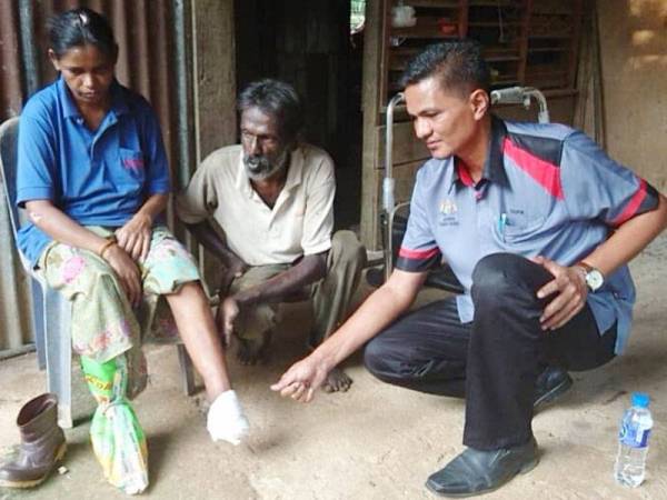 Pegawai Kebajikan DUN Taboh Naning, Taufiq (kanan) melihat keadaan isteri Sinniah.