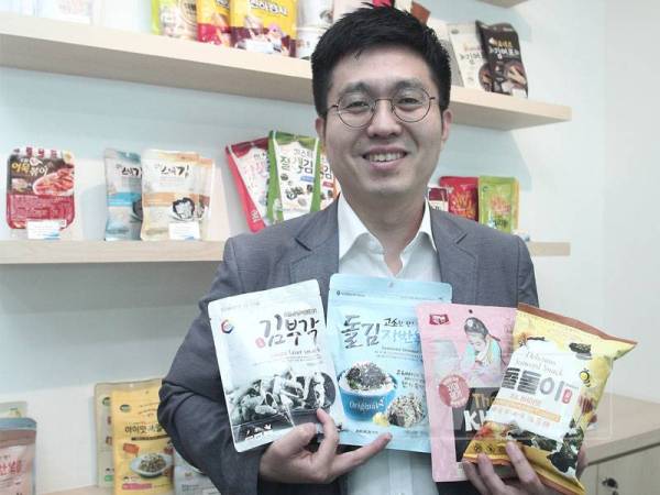 Lee Dong Jun menunjukkan produk terbaru Gim atau rumpai laut keluaran Korea yang dipasarkan di negara ini. - FOTO ZAHID IZZANI