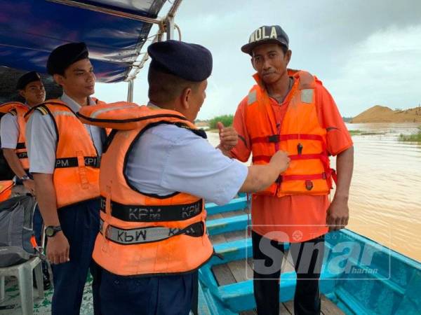 Muhammad Nur Syam memakaikan jaket keselamatan kepada Hazwadi Mohamad disini.