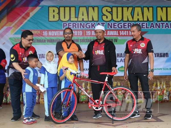 Wan Roslan (tengah) menyampaikan hadiah cabutan bertuah kepada pemenang.