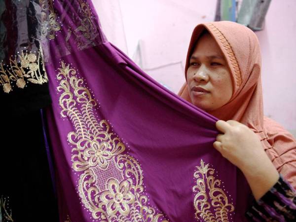 Walaupun Malikah Cholil cacat penglihatan tetapi dia dapat menyebut harga pakaian yang dijual menerusi sentuhannya. - Foto Bernama