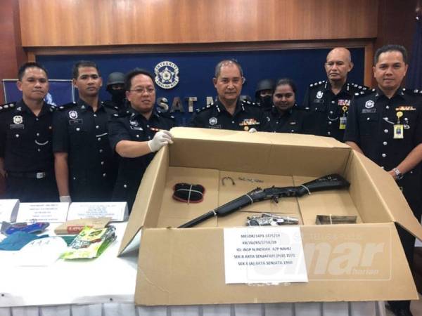 Abdullah (tengah) bersama barisan pegawai menunjukkan senapang dan pistol yang dirampas daripada kedua-dua suspek.