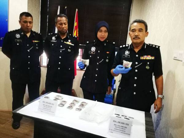 Adzli (kanan) menunjukkan dadah yang dirampas ketika serbuan dilakukan di Gurun pagi kelmarin.