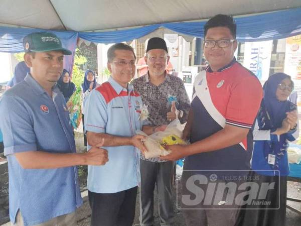 Syed Ibrahim (dua dari kiri) menyampaikan beras kepada penduduk sempena program Tukar Sampah Kepada Beras Ahad lalu.