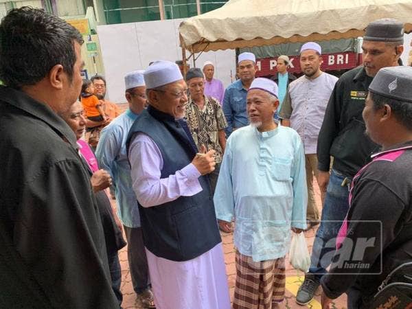 Ahmad (dua, kiri) sempat berbual dengan orang ramai selepas menyampaikan kuliah Jumaat di Medan Ilmu di sini.