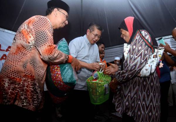 Salahuddin (tengah) menyampaikan sumbangan kepada sebahagian daripada 150 penerima fakir miskin kawasan Parlimen Tasek Gelugor pada Majlis Makan Malam dan Penyampaian Sumbangan Parti Amanah Negara malam tadi. -Foto Bernama