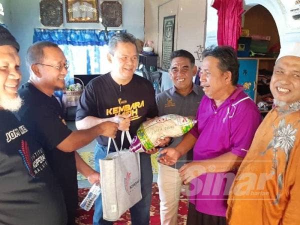 Ariffin (tiga dari kanan) menyerahkan sumbangan kepada keluarga asnaf di Kampung Ulu Chepor hari ini. 