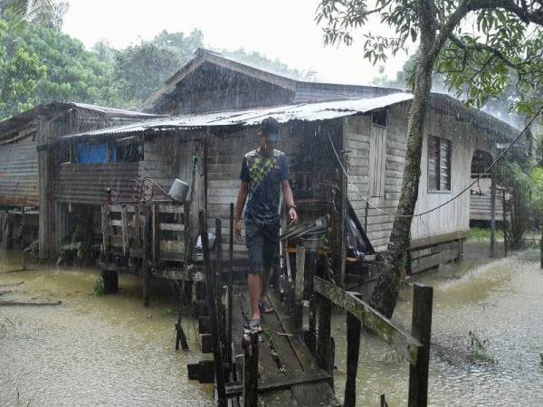 Mangsa banjir Muhammad Haikal Idani Razali, 15, menggunakan titi di belakang rumahnya selepas rumah keluarganya dilanda banjir di Kampung Tembak Baru, Wakaf Tapai kelmarin.