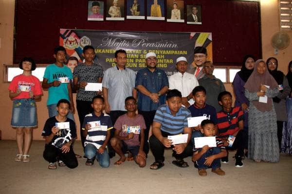 Mujahid (berdiri, lima dari kiri) bersama sebahagian daripada penerima baucar pakaian sekolah pada majlis perasmian Sukaneka dan Penyampaian Baucar Pakaian Sekolah Parlimen Parit Buntar dan Dewan Undangan Negeri (DUN) Selinsing hari ini. - Foto: Bernama
