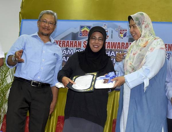 Zuraida (kanan) menyerahkan replika kunci PPR Taman Sri Bukit Tawau kepada ibu tunggal Puljiah Husen, 53, yang ketika ini menetap di Kampung Pasir Putih, hari ini. -Foto Bernama
