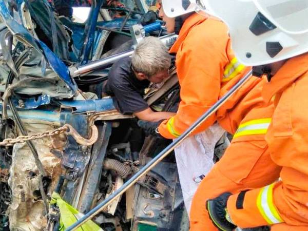 Anggota bomba sedang menyelamatkan Kamal Rosri yang tersepit selepas lorinya terjatuh dari ketinggian 30 meter. -Foto ihsan bomba
