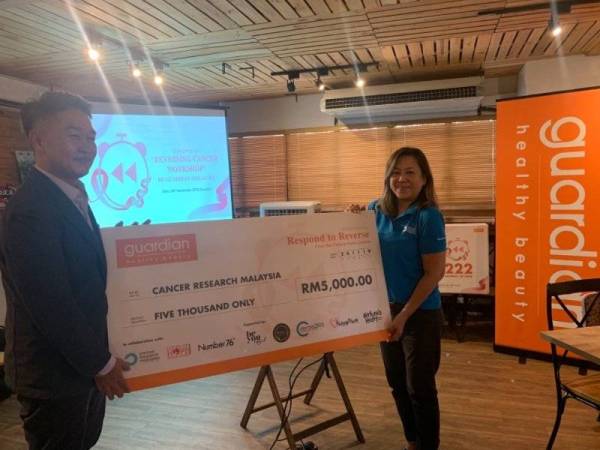 Do Youn Cho menyampaikan replika cek kepada wakil Canser Research Malaysia.