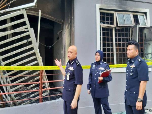 Anuar (kiri) menunjukkan kesan letupan yang menyebabkan pagar pintu gelongsor tertanggal dalam kejadian itu.