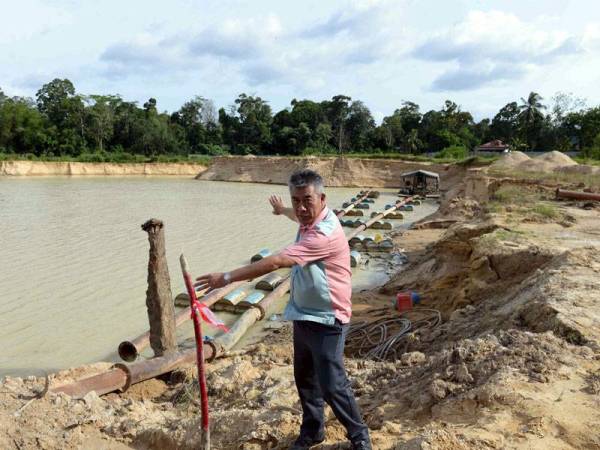 Mohamad menunjukkan had sempadan pencerobohan tanah untuk mengambil pasir ketika Ops Tiris di Kampung Kepala Batu, Pelubang hari ini. - Foto Bernama