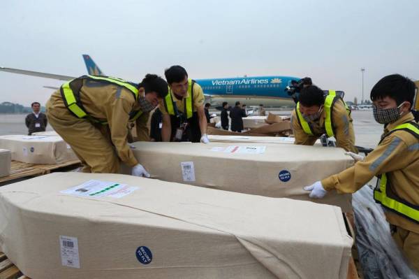 Kakitangan lapangan terbang memindahkan mayat mangsa sejurus ia tiba di lapangan terbang Hanoi. - Foto AFP