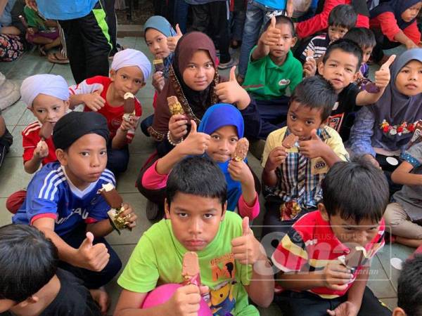 Solehin (tengah) bersama rakan yang lain menikmati aiskrim Magnum yang disediakan pada majlis tersebut.