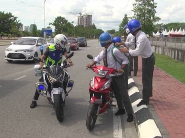 Anggota polis menahan kumpulan pelajar yang dipercayai melakukan lagak ngeri semasa menunggang motosikal. - Foto ihsan PDRM