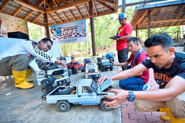 SHAHRIN (kanan) sedang memeriksa crawler kawalannya sebelum beraksi bersama peserta lain di Kejohanan Asia Skala Crawler 2019 di Taman Botani Nasional Shah Alam.