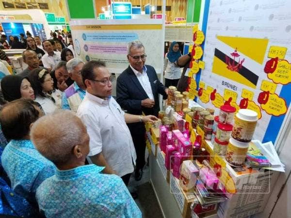 Abdul Fattah (dua dari kanan) dan Mohd Redzuan (kanan) melihat produk di reruai koperasi dari Brunei yang mempromosikan produk pada karnival itu.