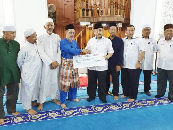 Abdul Fattah (lima dari kanan) menyerahkan replika cek berjumlah RM5,000 sumbangan untuk asnaf kariah Masjid Jamek As-Syakirin, Johor Bahru semalam.