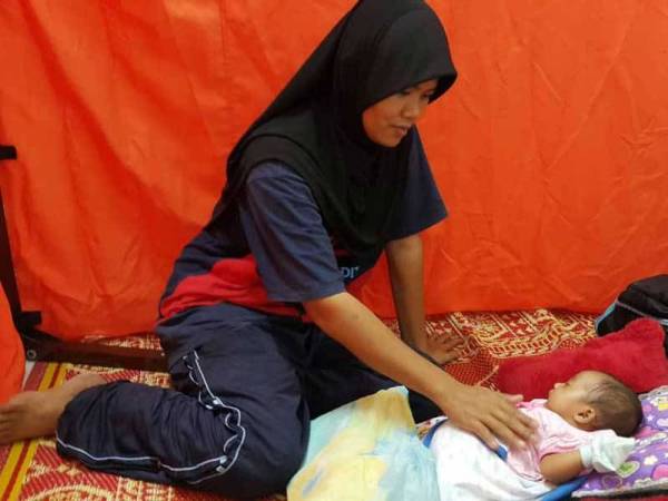 Surhaizam Taib menidurkan bayi perempuannya di pusat pemindahan Kampung Pengkalan Ajal.