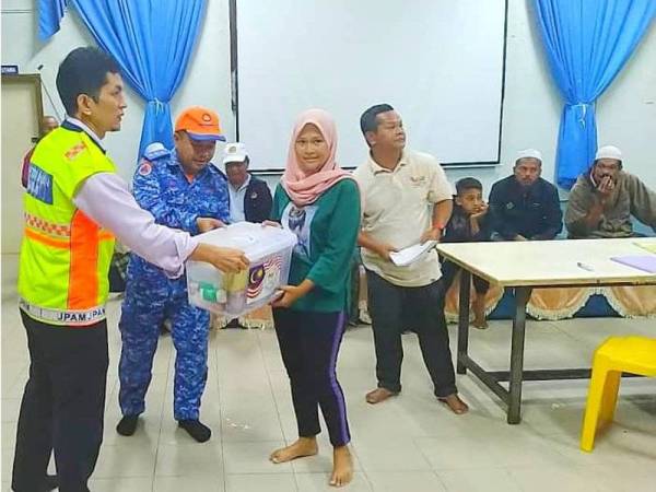 Pengerusi Pakatan Harapan Rantau Panjang, Dr Wan Shahjihan Wan Din (kiri) dan Mohd Arif menyampaikan bantuan kepada mangsa banjir di SMK (A) Lati.