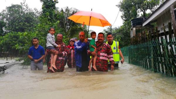 Anggota penyelamat dan Wan Hassan (dua dari kanan) menyelamatkan mangsa banjir di Kampung Gong Cokoh.