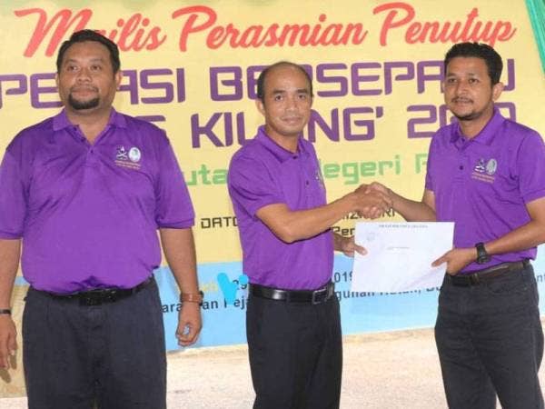 Grippin (tengah) menyampaikan sijil penyertaan kepada Penolong Pengarah Kanan Penguatkuasa Zon Pahang Timur Muhammad Firdaus Abdul Karim pada majlis penutup operasi bersepadu Op Kilang di pekarangan Pejabat Pembangunan Hutan Bukit Sekilau hari ini.